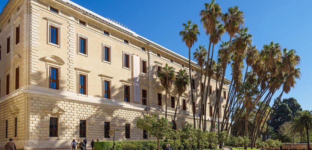 "Fachada del Museo de Málaga, ubicado en el histórico Palacio de la Aduana, con arquitectura neoclásica y palmeras al frente."